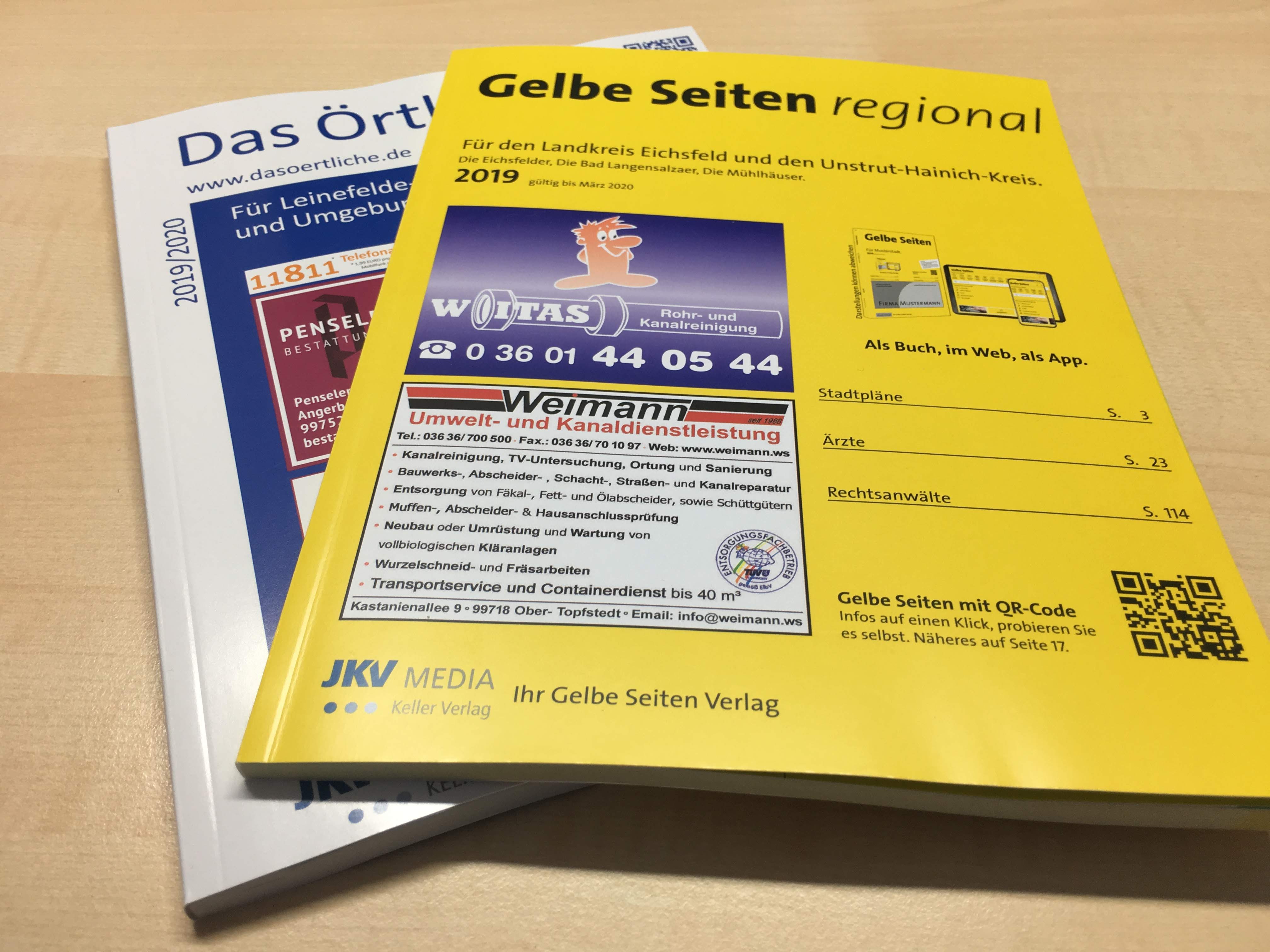 "Gelbe Seiten" und "Das Örtliche" liegen nebeneinander auf dem Schreibtisch, hier: wie man über Branchenbücher Werbung machen kann