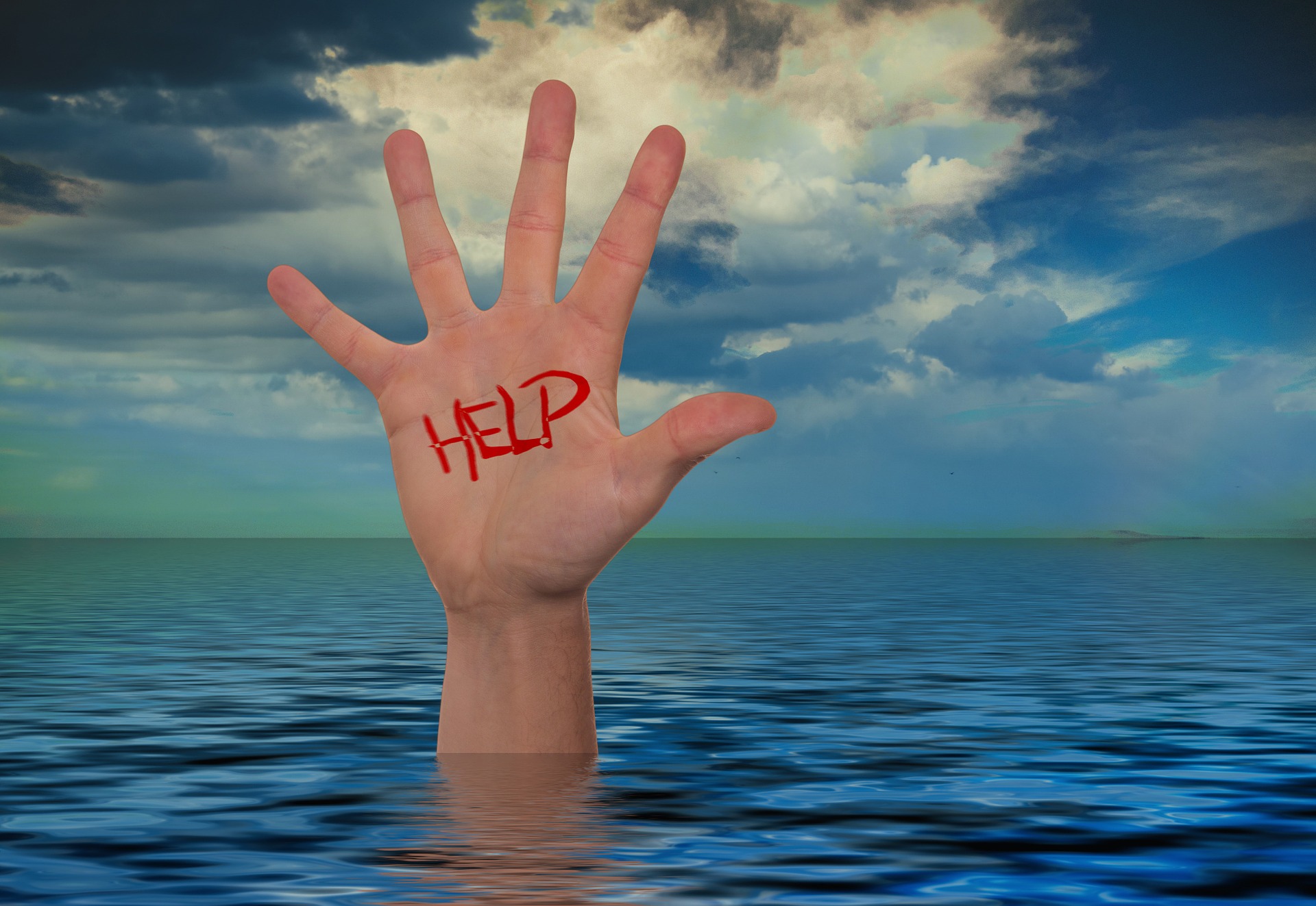 Meer, Hand, auf der Hand das Wort "Help" mit rotem Marker geschrieben