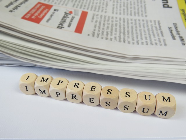 Vor einer Zeitung liegt auf einem Tisch das Wort Impressum Auswürfeln gebildet. Hier: Impressumsgenerator