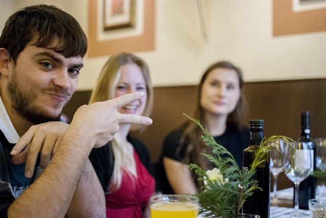 3 Praktikanten am Tisch. Einer davon hält die Hand mit gespreizten Fingern vor sich und grüßt. Hier Tipps zum Praktikum