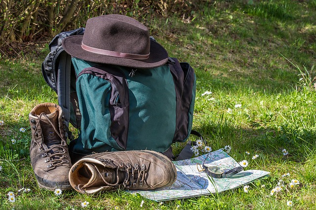 Reisekosten und Spesen berechnen, dazu auf dem Bild: Wandern, Landkarte, Orientierung, Wanderschuhe und Hut zu sehen