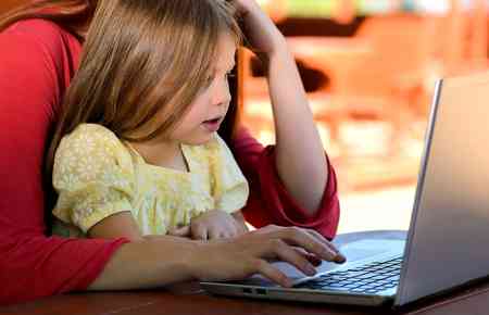 Kind mit Tagesmutter vorm Laptop